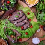 Cooked elk meat laid out across a bed of vegetables