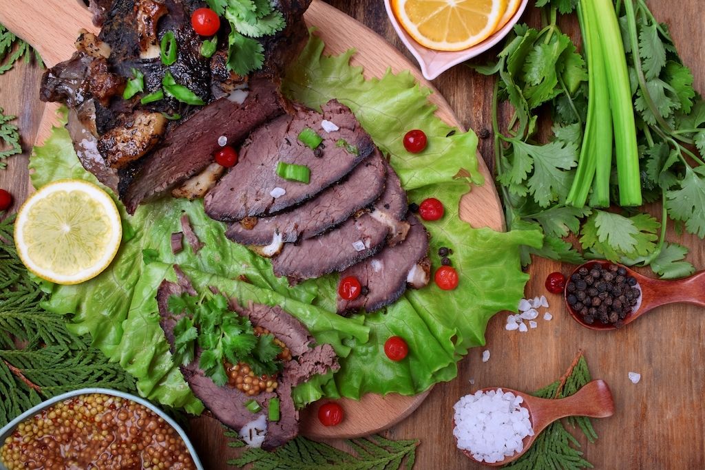 Cooked elk meat laid out across a bed of vegetables