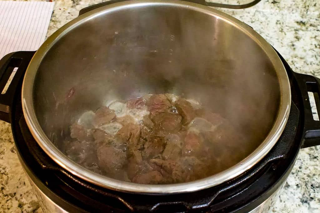Elk meat browning in the pot of a pressure cooker