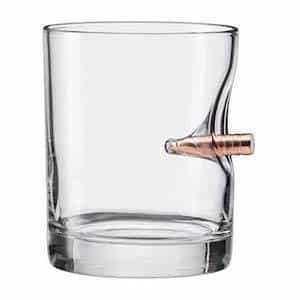 Rocks glass with a rifle bullet in the side of it