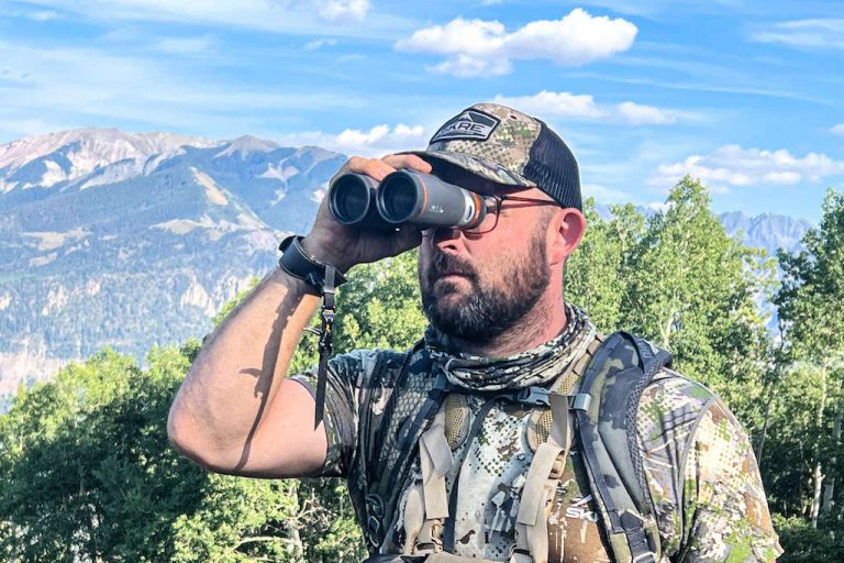 Hunter in a camo t-shirt glassing through a set of Maven hunting binoculars