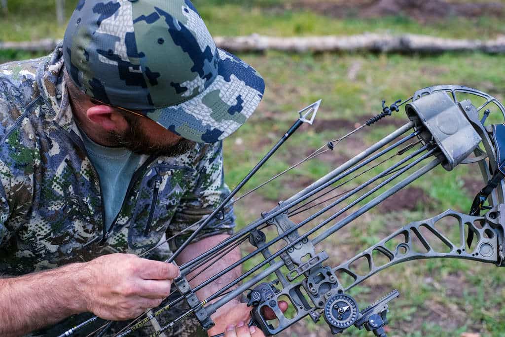 Man holding a carbon hunting arrow and putting it into a compound bow quiver