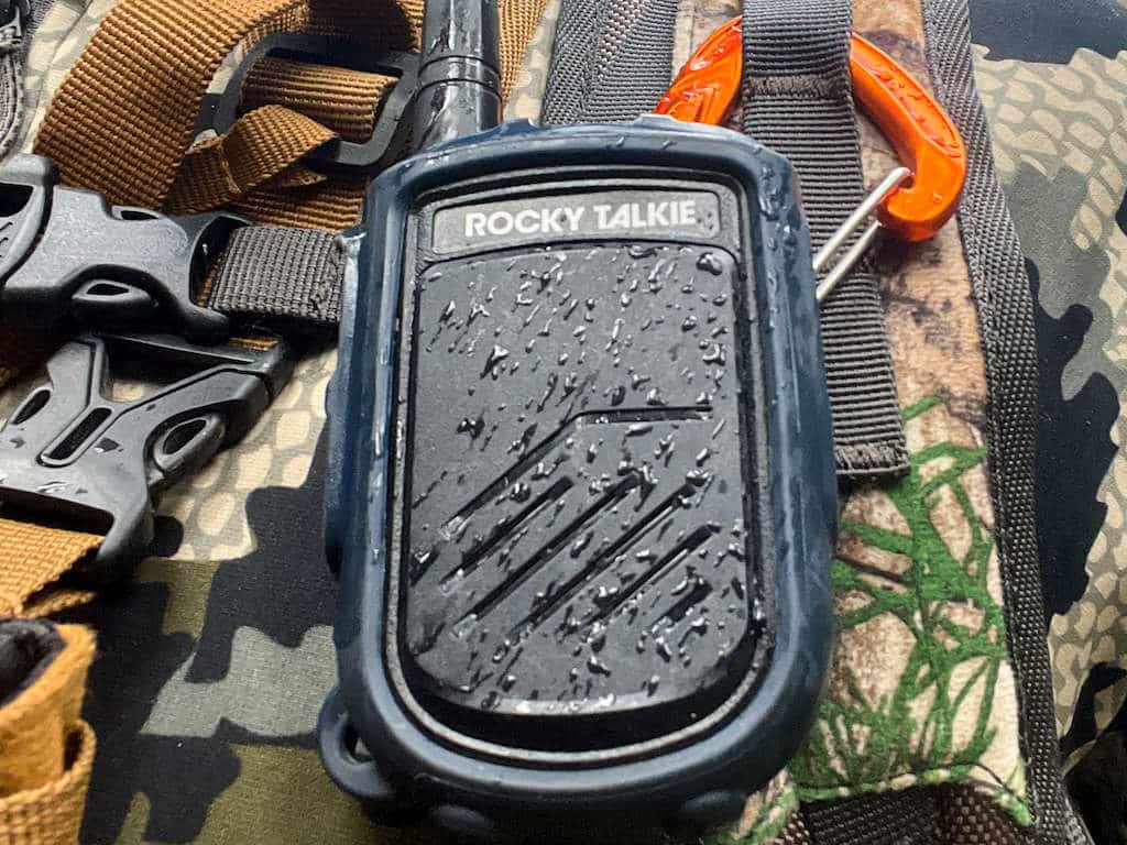 Hunter wearing camo and his two-way radio covered in precipitation demonstrating its weather resistance