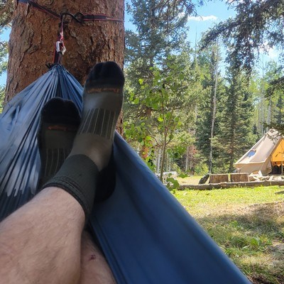 two feet laying in a hammock at camp. The feet have darn tough hunting socks on them