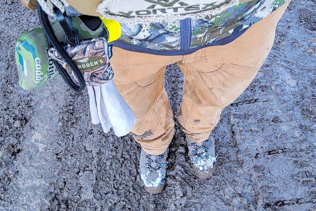 Hunter wearing camo looking down at the muddy earth
