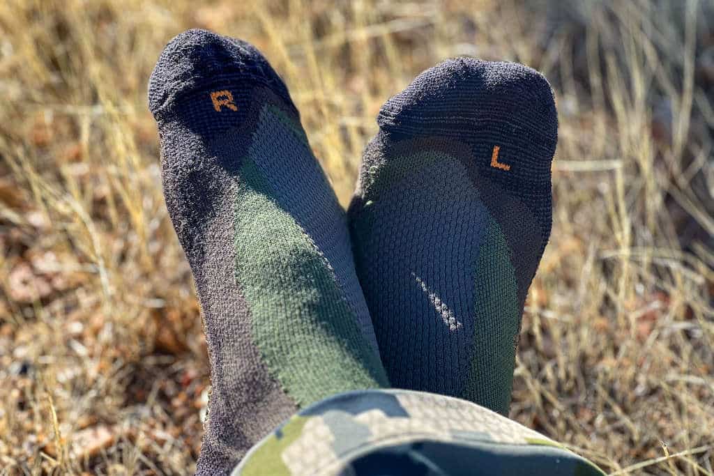 Hunter wearing camo kicking his feet up and showing off his merino wool socks