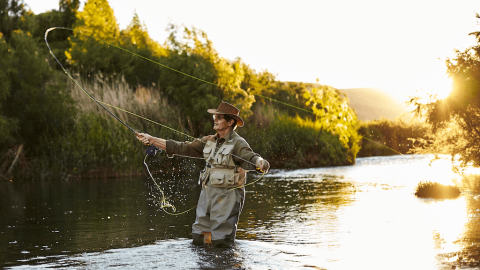 Man wearing a fishing vest while fly angling in a river