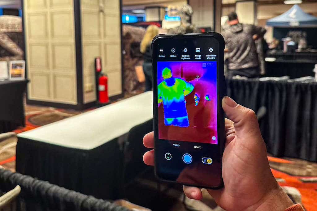 Man holding up a phone with a thermal signature of another man