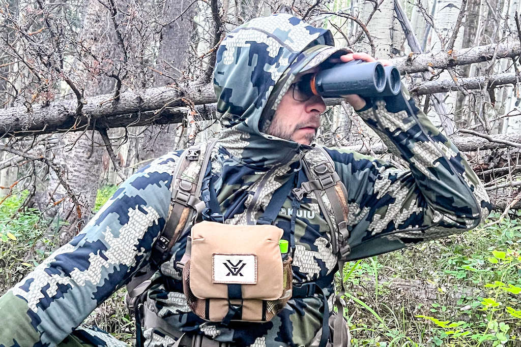 Hunter wearing KUIU camo and glassing through his binos in the forest