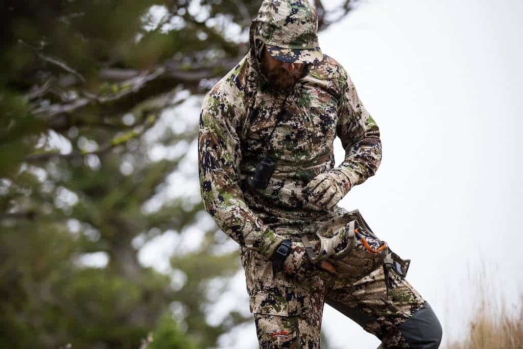 Hunter sorting through his binocular chest pack while wearing SITKA camo