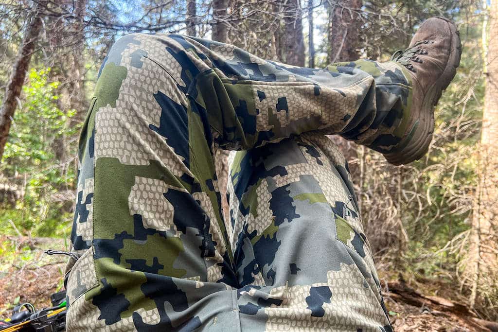 View of a hunters legs with his knee ankle propped up on his knee in KUIU camo