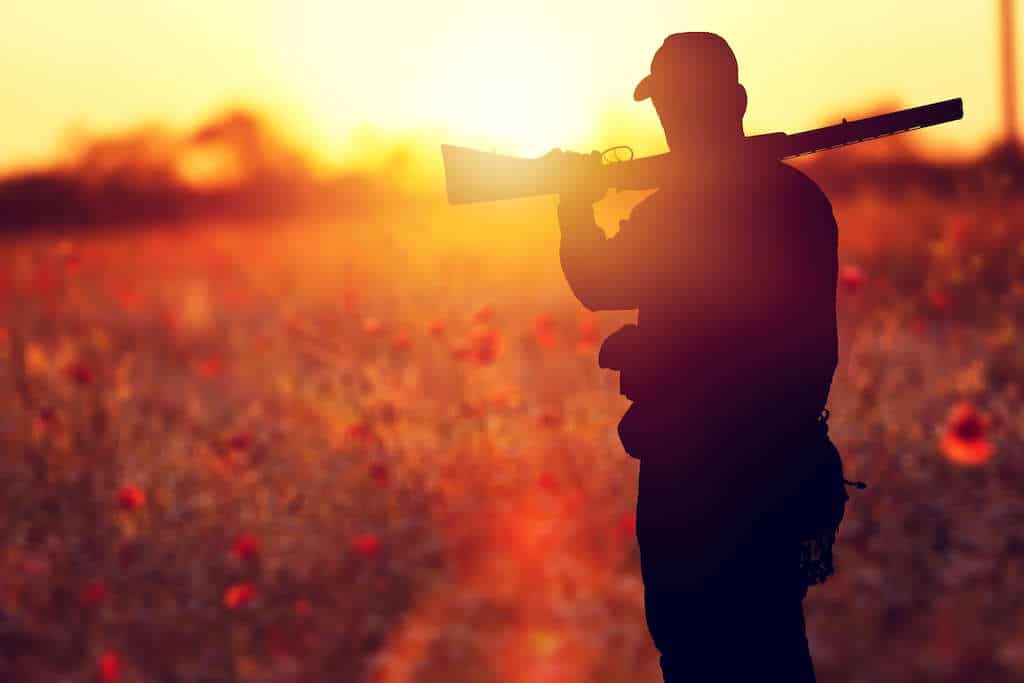 Ethical hunter with a gun resting on his shoulder at sunset