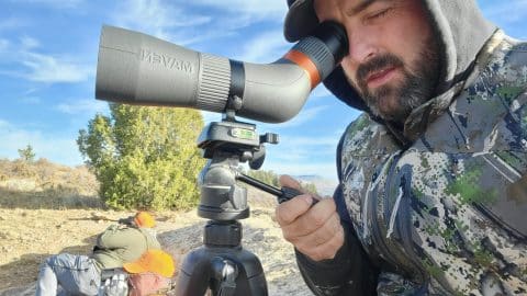 Final Stalk guide glassing through a Maven spotting scope on a Colorado rifle hunt with hunters behind him