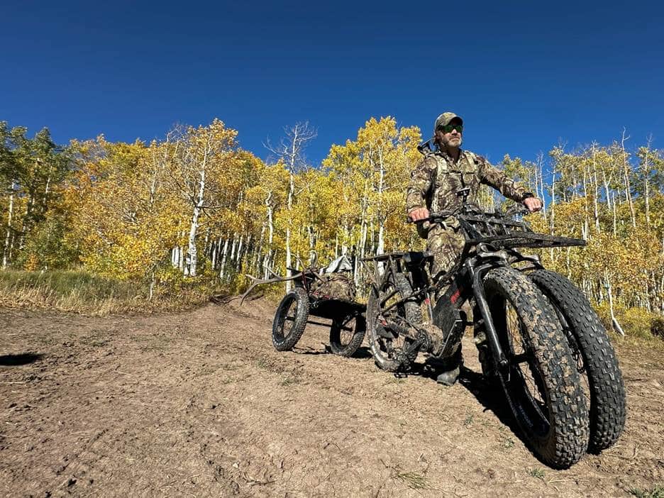 man on dual wheel electric bike tows an elk carcass in the trailer