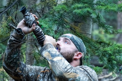 Elk hunter blowing a locate bugle through a bugle tube in Colorado timber during archery season