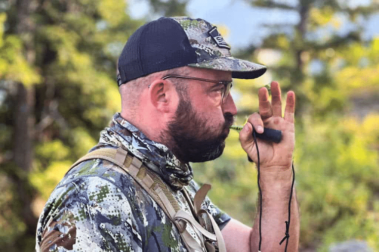 Elk hunter in Sitka camo running a diaphragm cow call in the field during archery elk season