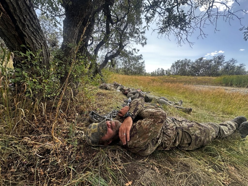 Bowhunters resting midday in Kryptek Highlander camo under an oak tree